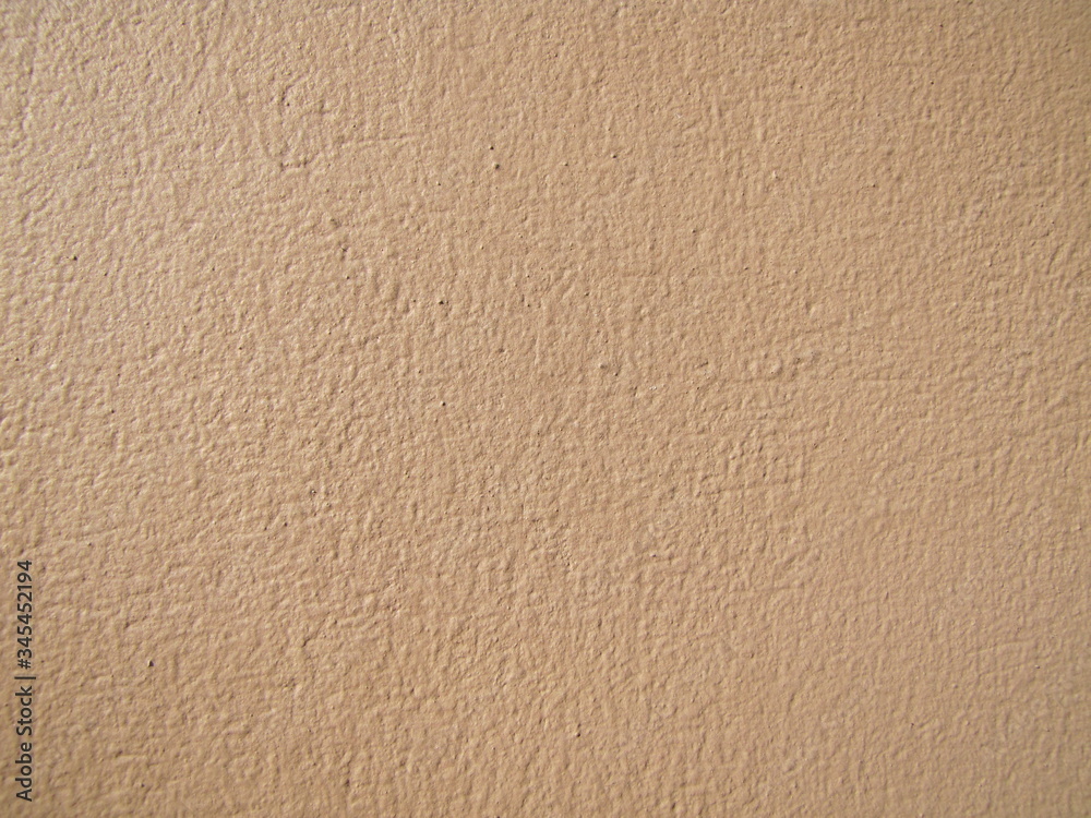 Textured exterior wall background and painted in pink brown color. Exterior plastered wall of exposed building illuminated by sunlight. Textured exterior wall background and painted in pink brown color. Exterior plastered wall of exposed building illuminated by sunlight.