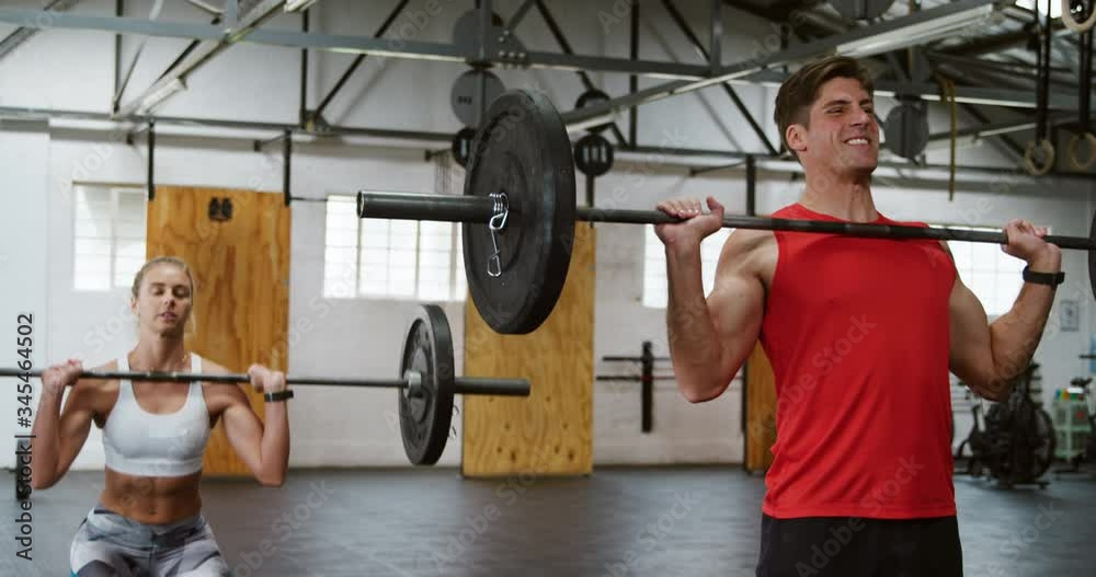 Front view of an athletic Caucasian man and woman training with barbells Front view of an athletic Caucasian man and woman training with barbells