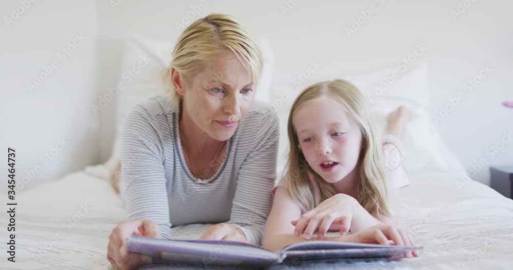 Front view of Caucasian woman reading a story to her daughter on bed Front view of Caucasian woman reading a story to her daughter on bed