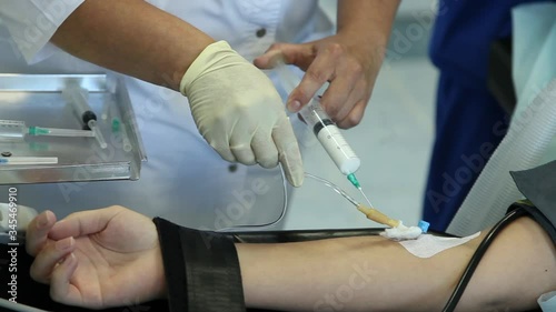 Nurse injects the white drug into a patient's vein with a syringe.Intubated patient connected to an artificial lung ventilation unit. photo