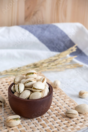 Bowl with pistachios on wooden background. pistachios with wood spoon and fork and Ears of rice on fabric background