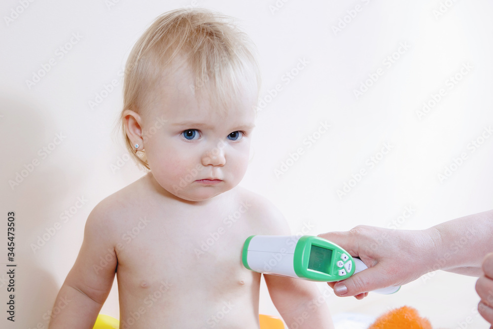 Digital non-contact thermometer and baby girl. Digital non-contact thermometer and baby girl.