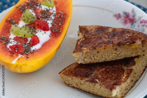 Breakfast with cinnamon banana cake, papaya topped with strawberries, grapes, plain yogurt and chia seeds