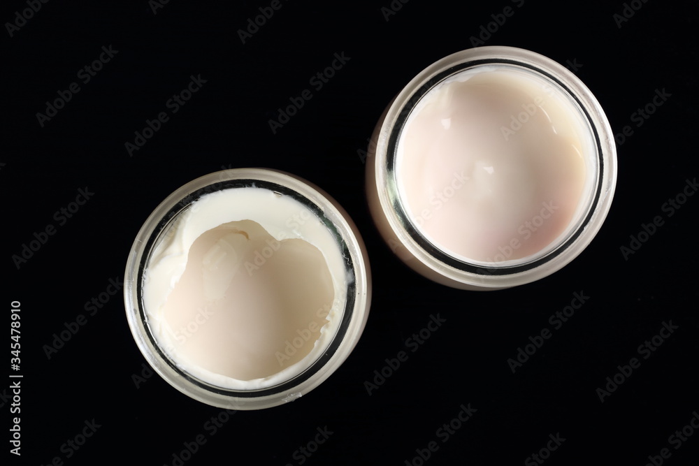 Yogurt in open small glass jar at black background. Directly Abo Yogurt in open small glass jar at black background. Directly Abo