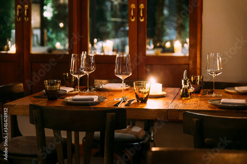 Crop image of romantic fine dining table with cutleries  plates  wine glasses  napkins and naperies on the table. Light source from candle light.