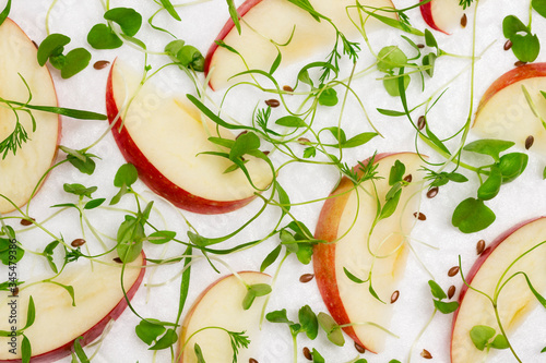Sliced apples with young microgreen sprouts on white background, healthy nutrition.