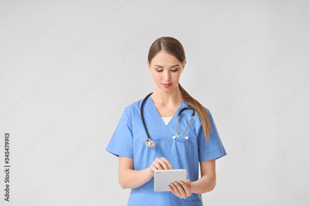 Young female doctor with tablet computer on grey background Young female doctor with tablet computer on grey background