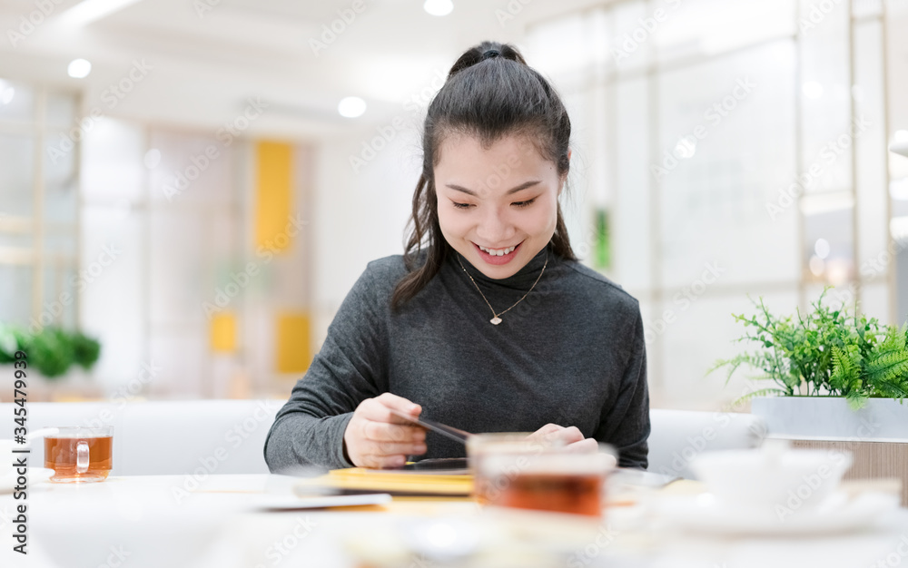 smiling woman in a restaurant with the menu in hands smiling woman in a restaurant with the menu in hands