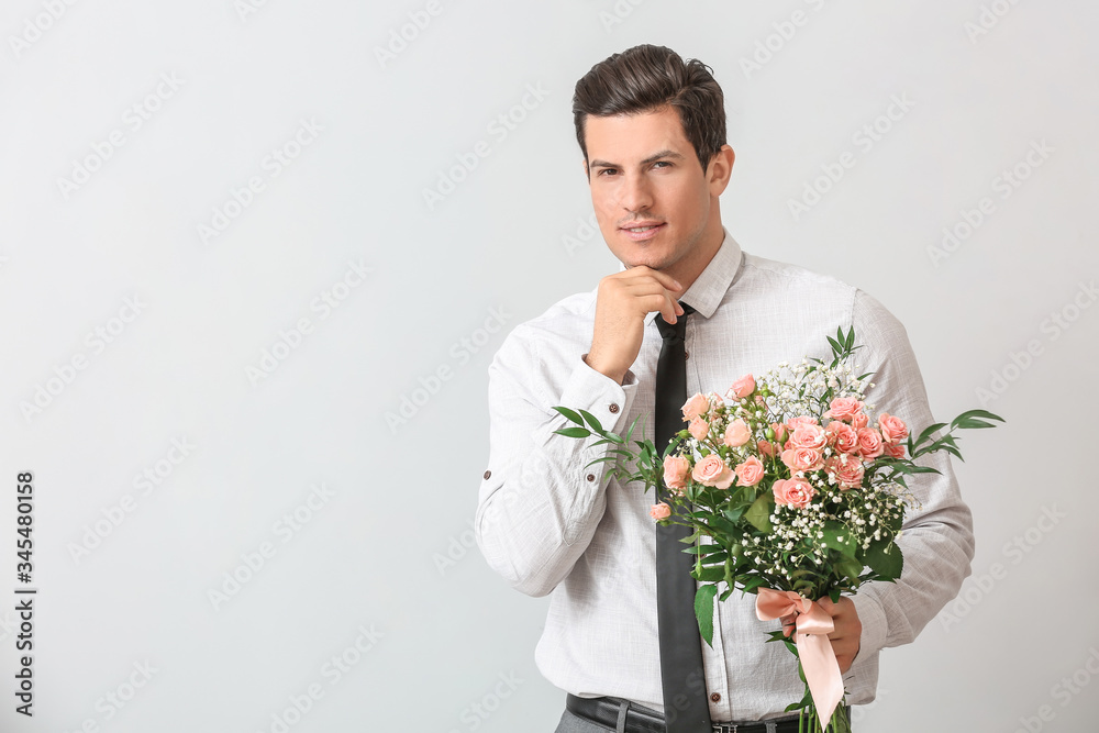 Handsome man with bouquet of flowers on light background Handsome man with bouquet of flowers on light background