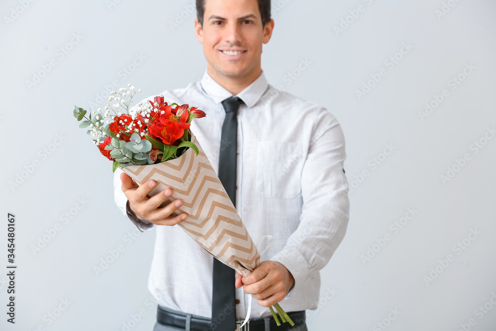 Handsome man with bouquet of flowers on light background Handsome man with bouquet of flowers on light background