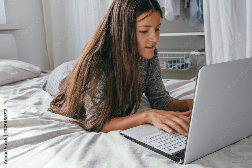 yong woman using laptop at home , woman lying on the bed and using computer yong woman using laptop at home , woman lying on the bed and using computer