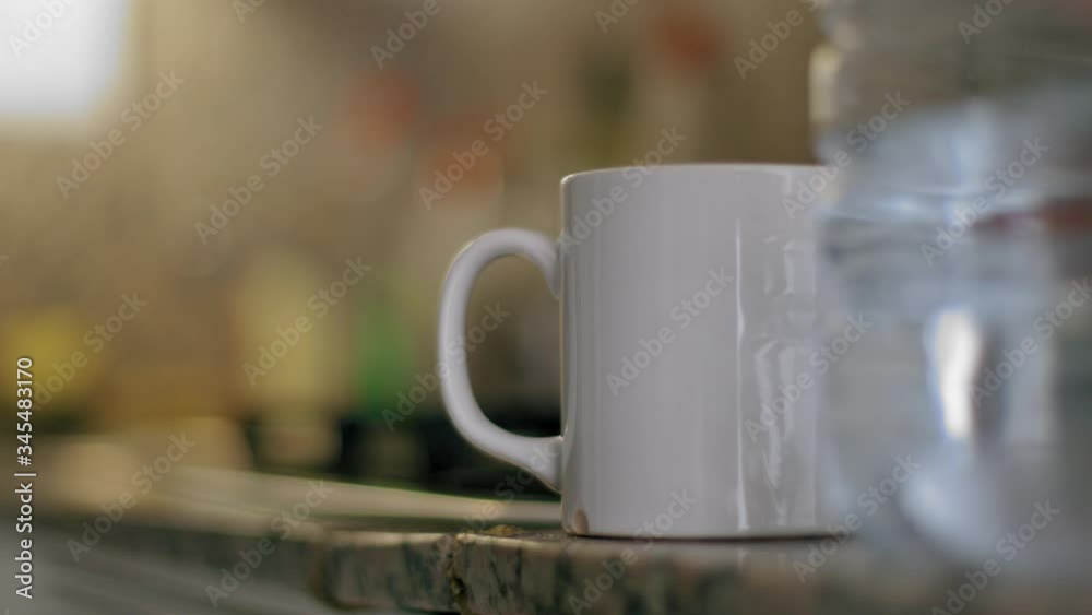 Detail shot of a man grabbing a plastic bottle and pouring water to a cup close up shot at home in the kitchen at night Detail shot of a man grabbing a plastic bottle and pouring water to a cup close up shot at home in the kitchen at night