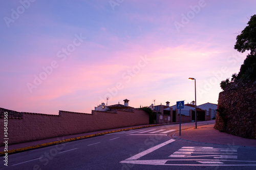 Street lamp illuminates a crosswalk at a crossroads against the sky during sunset