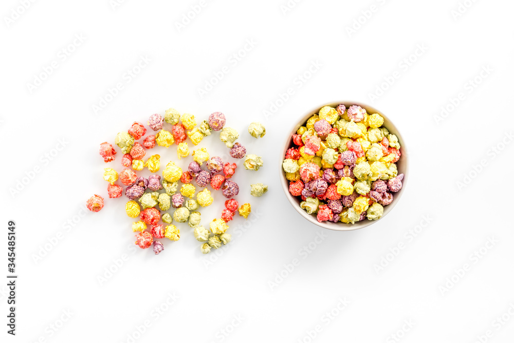 Colored popcorn in bowl on white background top view