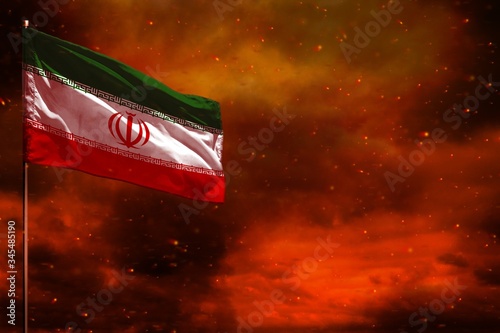 Fluttering Iran flag mockup with blank space for your text on crimson red sky with smoke pillars background. Troubles concept.