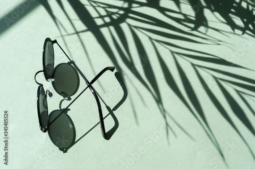 sunglasses and floral palm shadows on mint background top view. Flat lay creative fashion lifestyle .