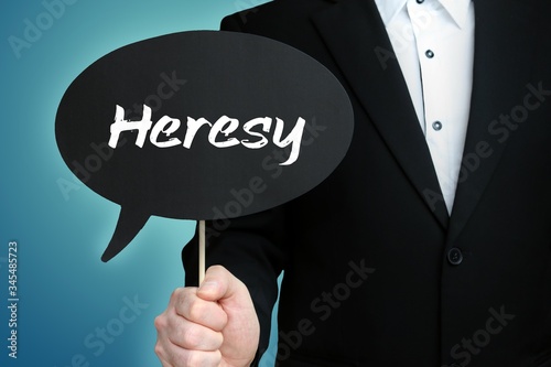 Heresy. Lawyer in suit holds speech bubble at camera. The term Heresy is in the sign. Symbol for law, justice, judgement photo