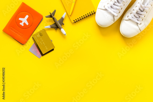 Tavelling background - airplane, shoes, notebook, passport - on yellow table from above copy space