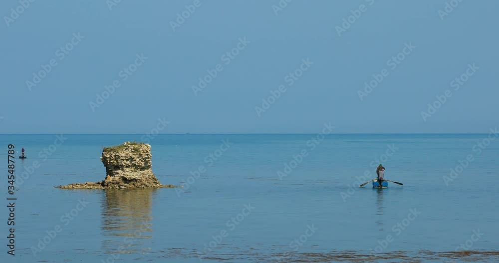Fishermen with boats sailing slowly on shallow lagoon of sea near ruins of Medieval Castle on shore of Mediterranean Fishermen with boats sailing slowly on shallow lagoon of sea near ruins of Medieval Castle on shore of Mediterranean