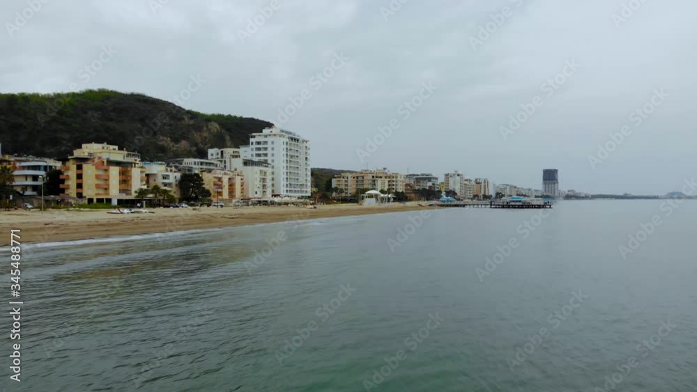 Adriatic coast in Durres Albania on a cloudy day, calm sea reflecting buildings of holiday resorts on wide sandy beach