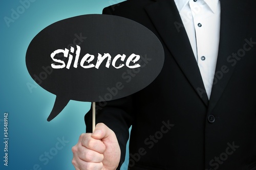 Silence. Lawyer in suit holds speech bubble at camera. The term Silence is in the sign. Symbol for law, justice, judgement