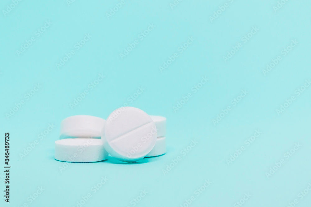 white a round pills on a blue background close-up medical treatment copy space concept white a round pills on a blue background close-up medical treatment copy space concept