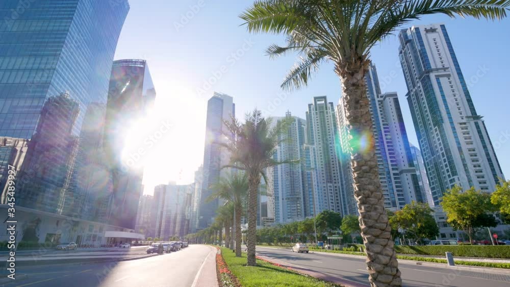 Bright white sun shines between tall skyscrapers in downtown tropical Dubai