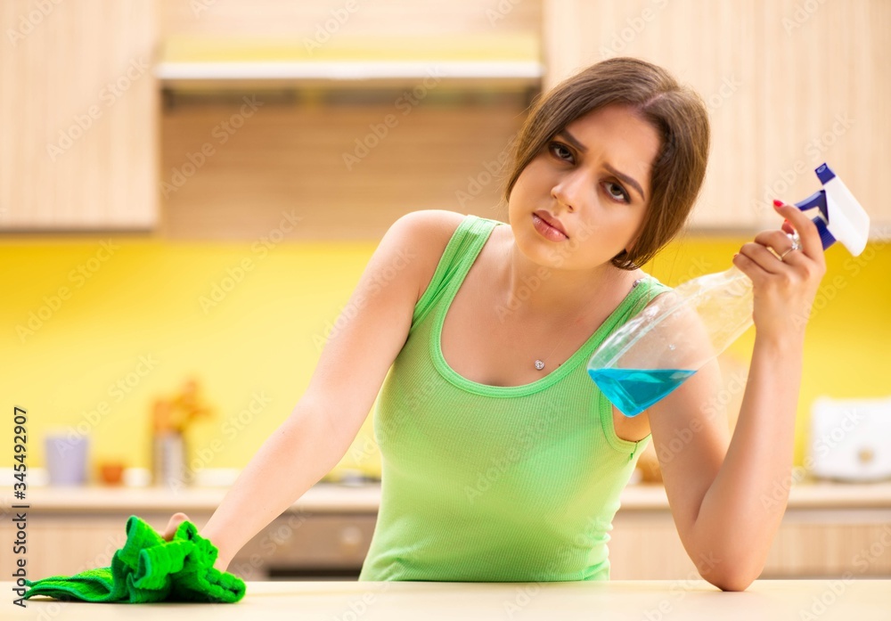 Young beatifull woman polishing table in the kitchen Young beatifull woman polishing table in the kitchen