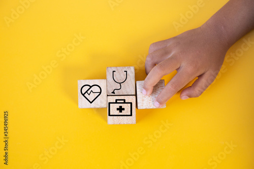 Children hands holding wood cube with a medical symbol,Concept: Health insurance family covid-2019 epidemic,.management protect healthcare to a virus,care service doctor treatment for hospital.