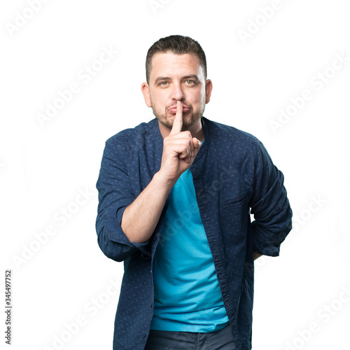 Young man wearing a blue outfit. Doing silence gesture.