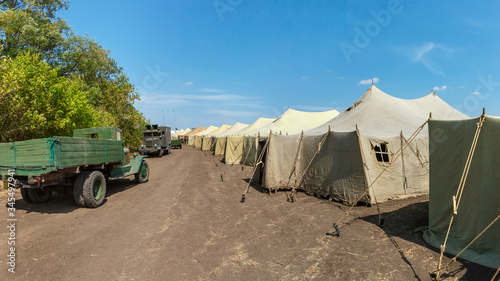 A big military World War II soviet tent camp with old trucks on a road