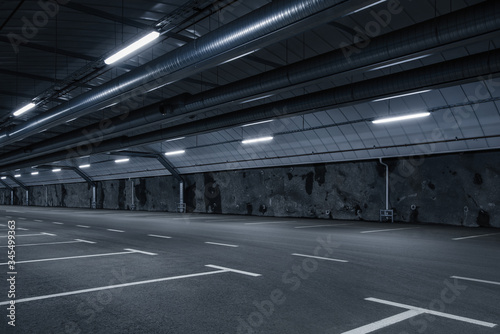 Sci fi looking empty, dark and moody underground parking lot with fluorescent lights on. Long hall