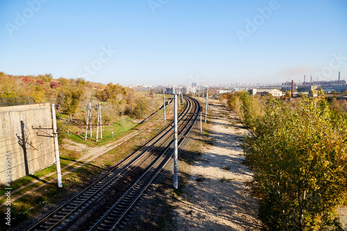 Fototapeta Naklejka Na Ścianę i Meble -  View on railway from high place and trees arround in summer or autumn day. Nice lanscape with city and nature