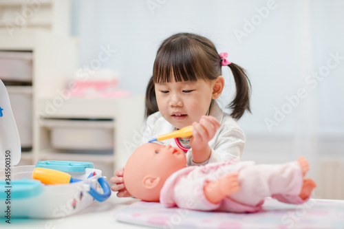 toddler girl pretend play doctor role  at home against white background