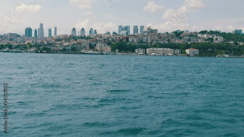 Istanbul, Turkey - June 12, 2019: Rich luxury quarter of residential buildings on green hills by the sea that are surrounded by greenery against the background of large skyscrapers of business centers photo