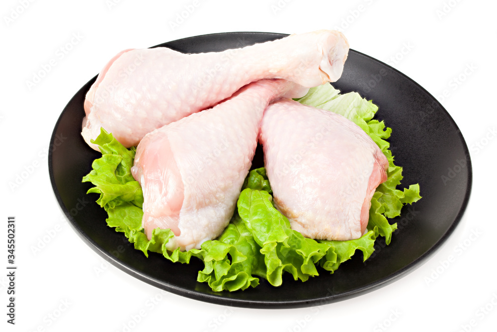 Raw chicken legs on black plate isolated on white background