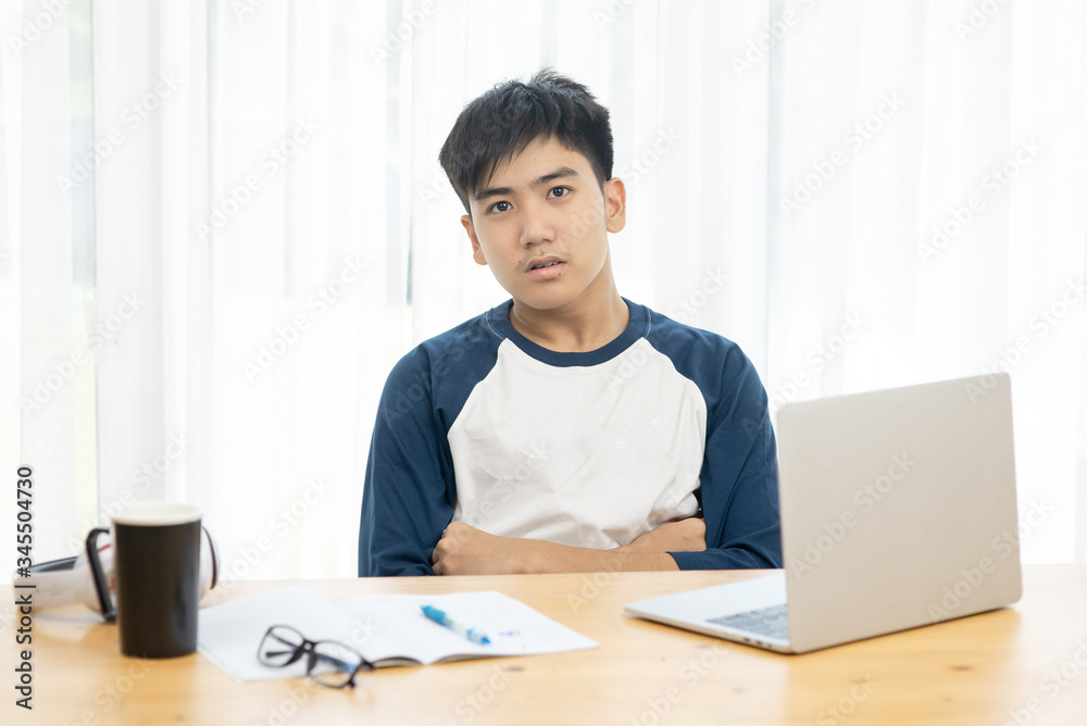 Asian teenager using laptop for home schooling concept during corona virus, crossed arms and looking at camera. Asian teenager using laptop for home schooling concept during corona virus, crossed arms and looking at camera.