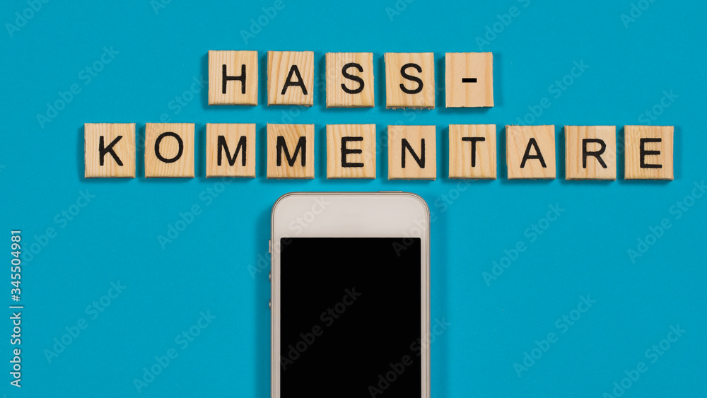 Hasskommentare im Internet Holzbuchstaben mit Handy Hasskommentare im Internet Holzbuchstaben mit Handy