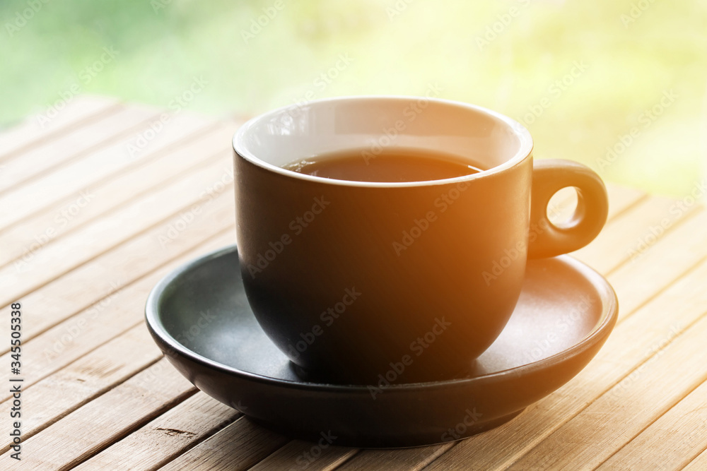 Cup of coffee on wooden table cloth in the open air with sun light flash effect
