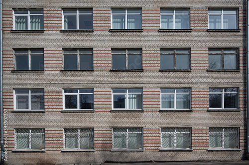 Facade of the Soviet panel grey with orange old building with windows. Typical school, hospital building made in USSR.