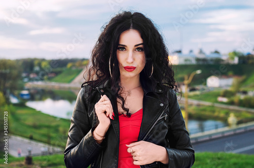 Fashion woman posing outdoor. leather jacket,brunette hair, bright red lips. Street fashion concept.