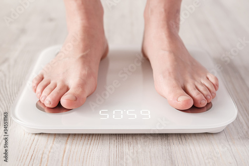 Bare feet stand on smart scales that makes bioelectric impedance analysis, BIA, body fat measurement.