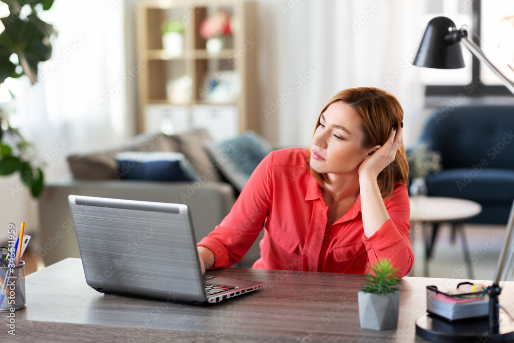 remote job, technology and people concept - bored or tired young woman with laptop computer working at home office