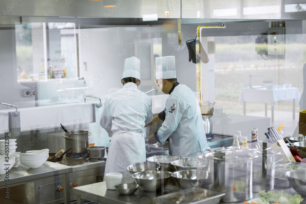 Two chefs who cook in white chef uniforms Going to cook in the kitchen to serve food to customers in the hotel restaurant Two chefs who cook in white chef uniforms Going to cook in the kitchen to serve food to customers in the hotel restaurant