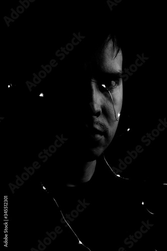 Portrait on a black background a man with lights from light bulbs.