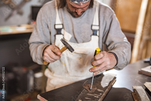 Male carpenter working on old wood in a retro vintage workshop.