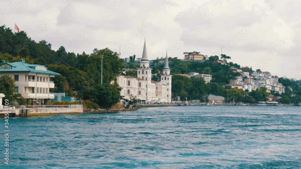 A rich luxury quarter of residential buildings on green hills on the seashore that are surrounded by greenery. View from a passing boat, Istanbul, Turkey