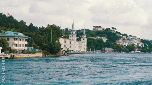 A rich luxury quarter of residential buildings on green hills on the seashore that are surrounded by greenery. View from a passing boat, Istanbul, Turkey photo