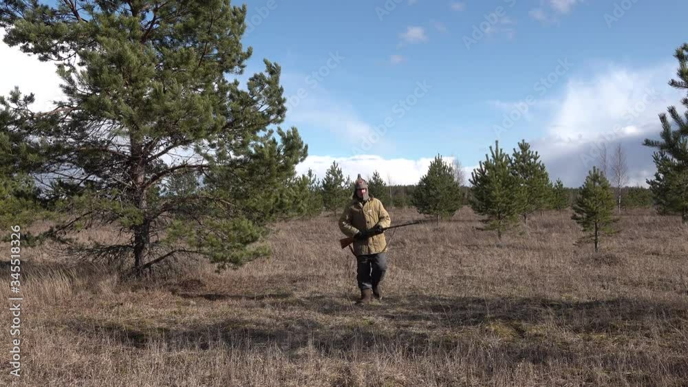 Man hunter soldier Red Army going the forest field and shoots firing a shotgun Man hunter soldier Red Army going the forest field and shoots firing a shotgun