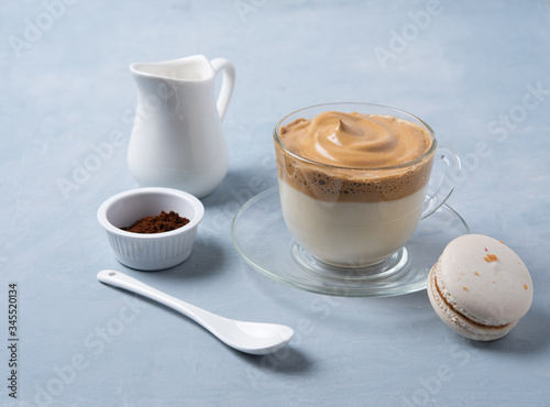  Korean dalgona coffee  in a glass Cup with macaroon, milk jug and instant coffee on light blue  background. Trendy  drink